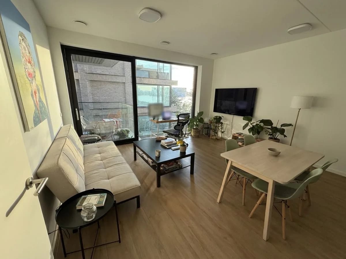 Living room as it is: a white sofa bed and a black coffee table by a large sliding window, a wall-mounted TV and a light dining table